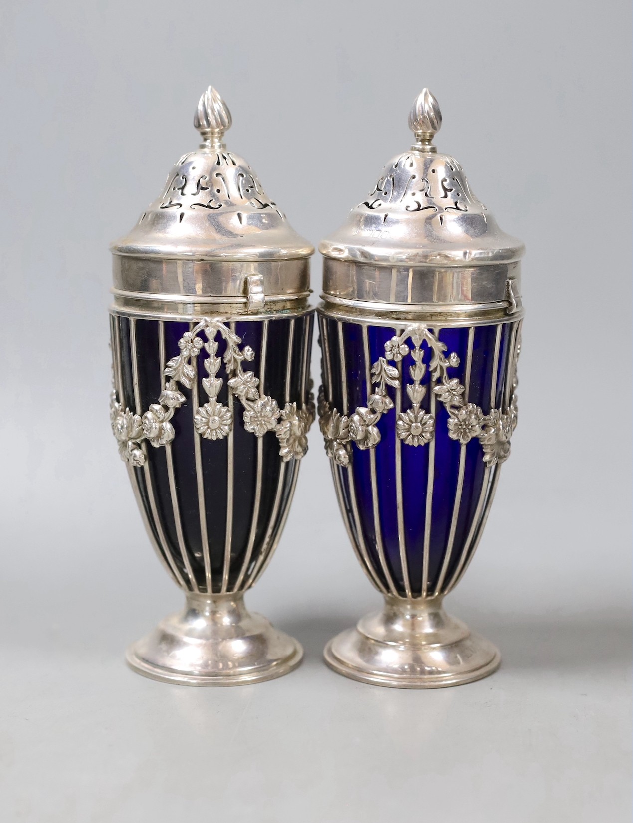 A pair of George V pierced silver sugar sifters, with blue glass liners, London, 1912, height 17.9cm.